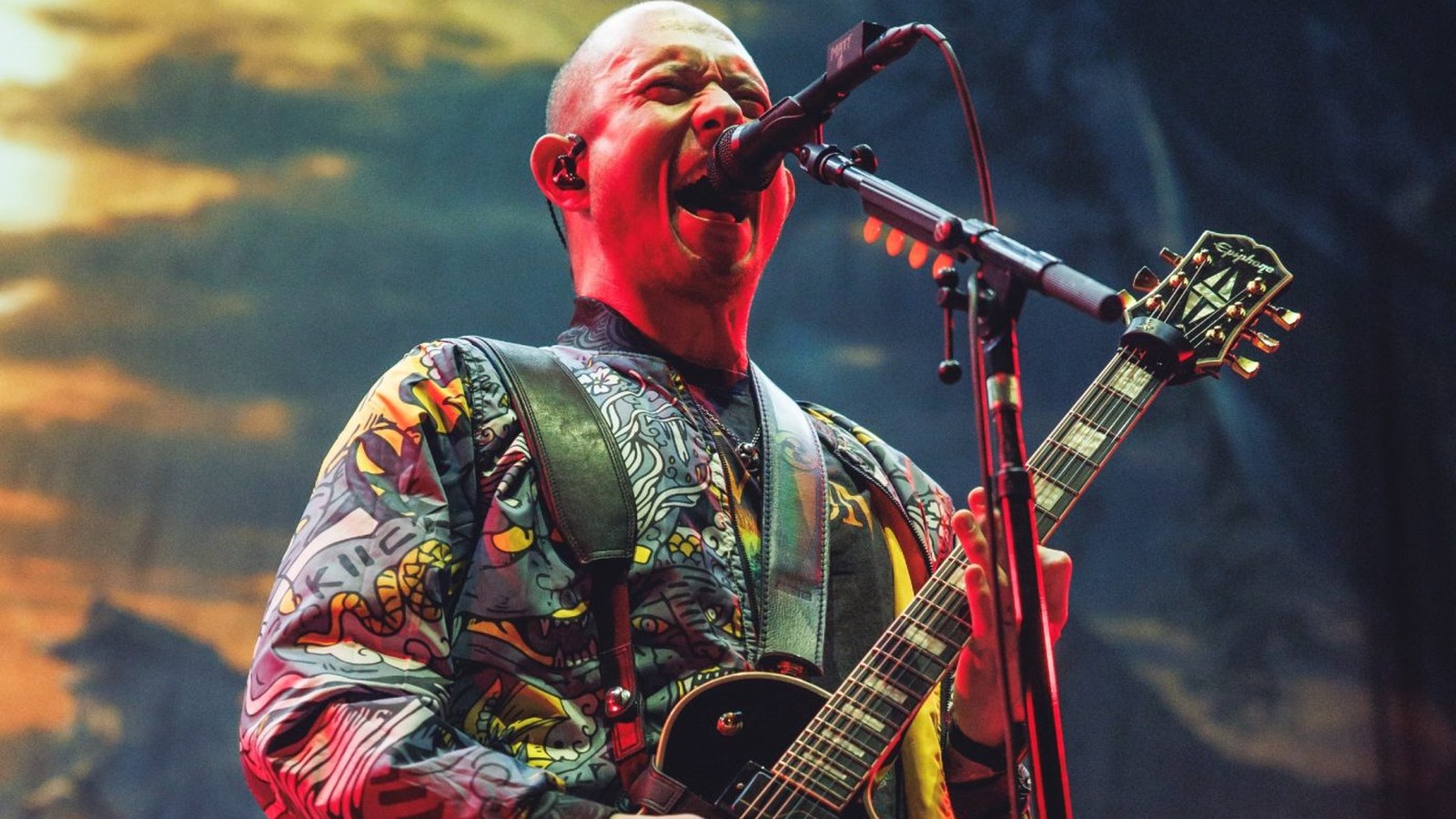 Matt Heafy cantando en vivo con Trivium, bajo luces rojas