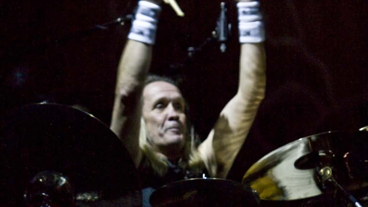 Nicko McBrain en vivo, con los brazos en alto detrás de su batería