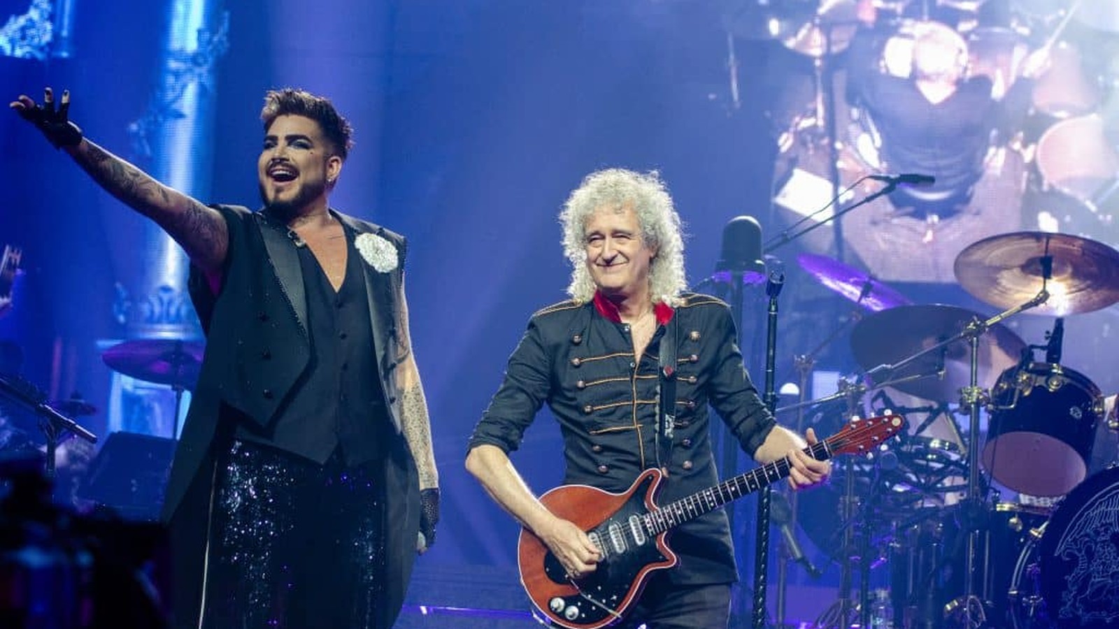 Adam Lambert y Brian May en vivo, con Roger Taylor en la pantalla de fondo